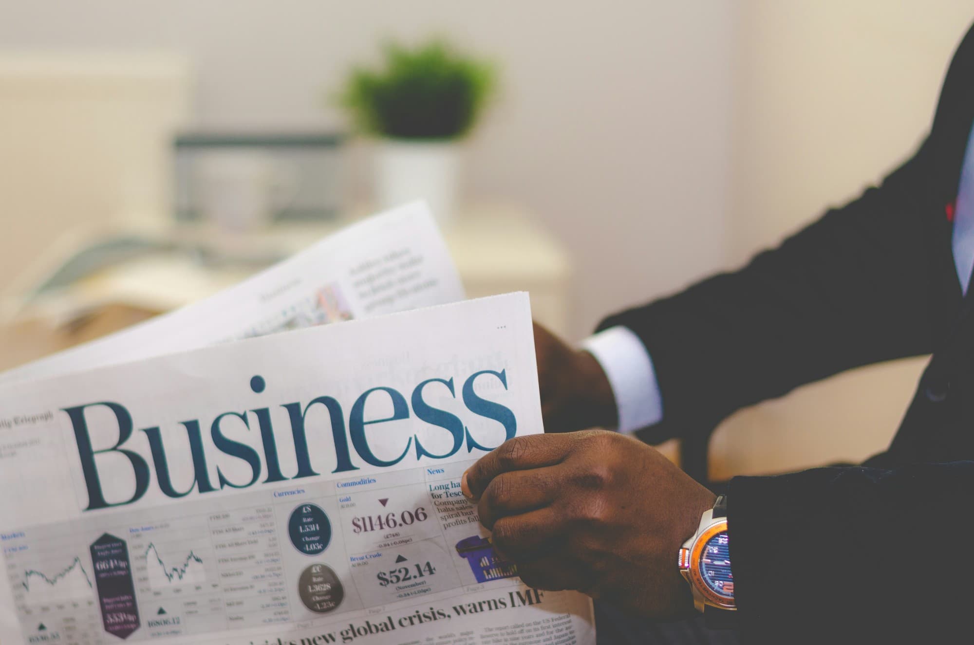 A person in a suit reading the business section of a newspaper